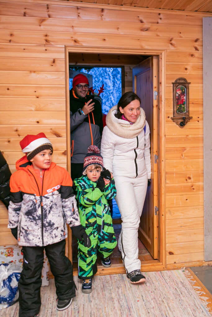 Copii lângă intrarea unei căsuțe festive de lemn