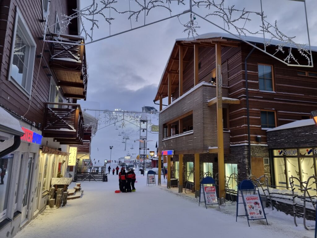 Stradă înzăpezită printre clădiri cu lemnărie exterioară