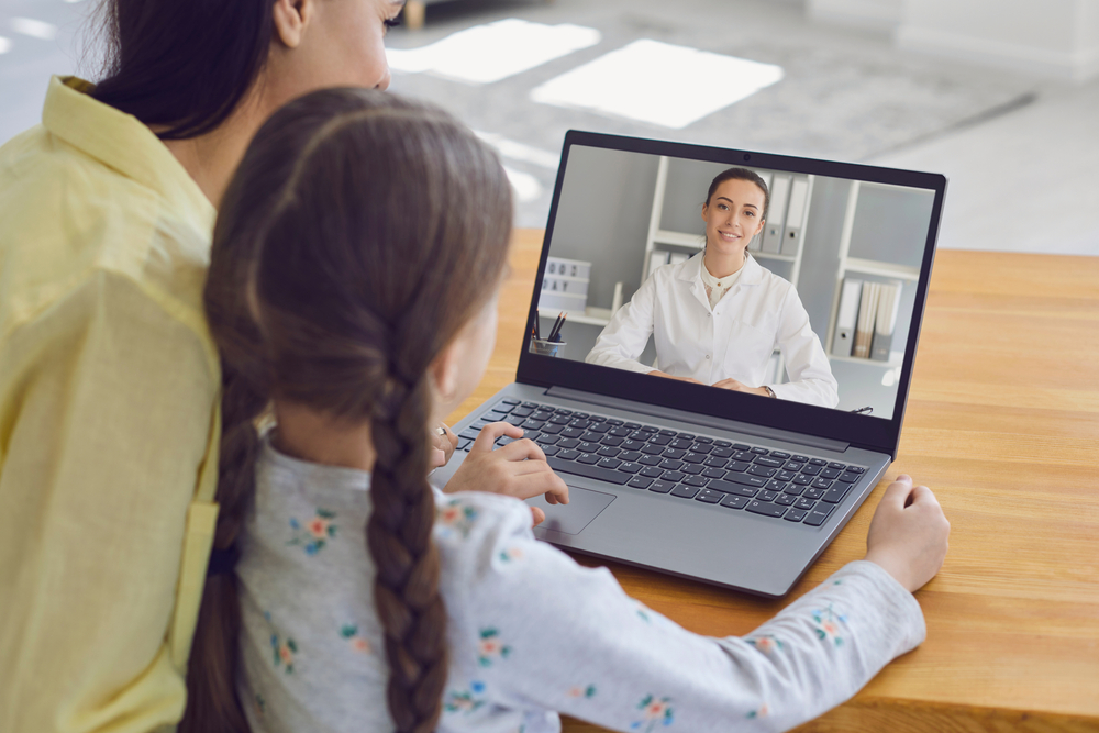 Femeie cu copil participând la un apel video pe laptop