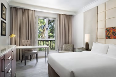 Cameră de hotel cu pat dublu, birou și fereastră spre grădină.