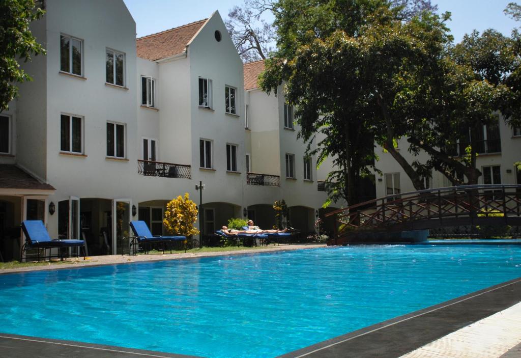 Piscină exterioară în fața unei clădiri albe cu mai multe etaje.