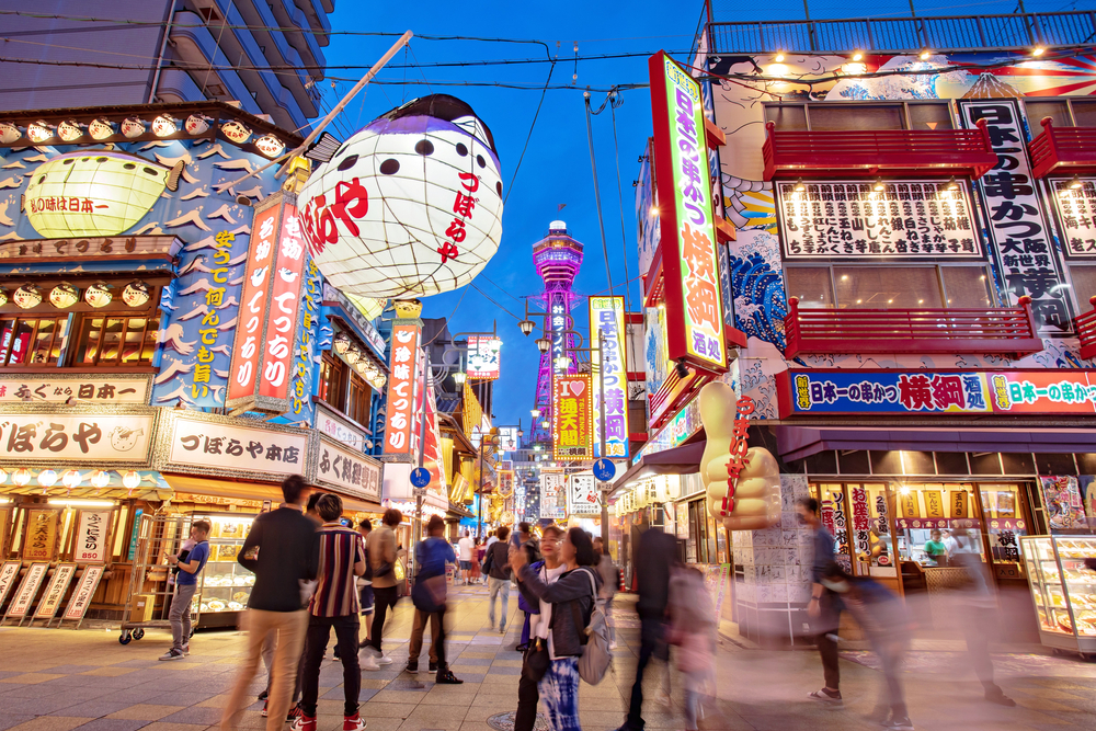 Stradă comercială aglomerată în Osaka, cu reclame colorate