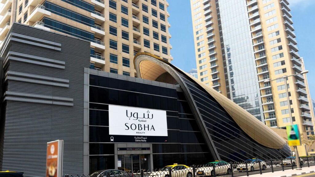 Intrare de metrou cu panou Sobha, între clădiri