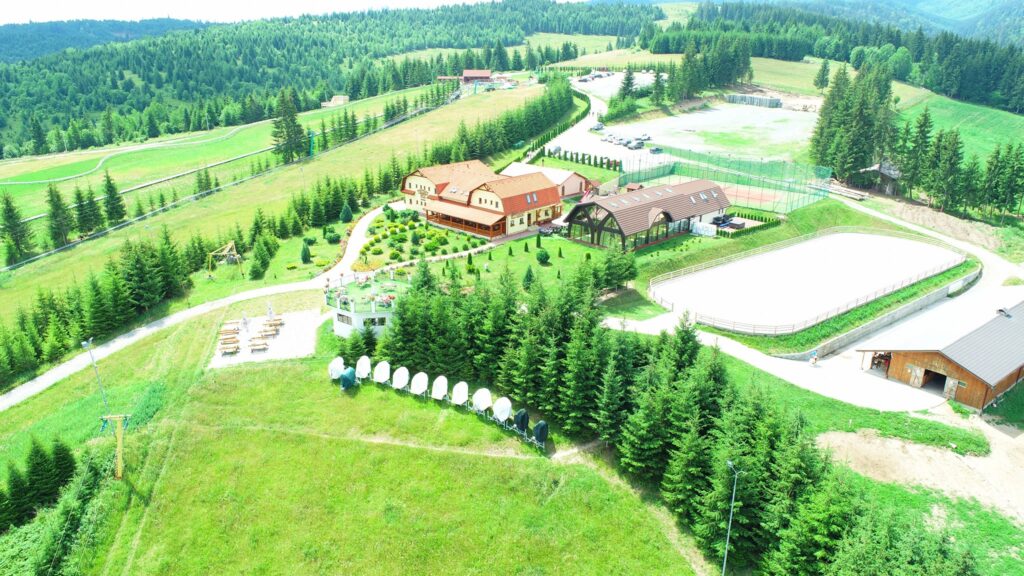Pensiune și terenuri amenajate, înconjurate de pădure
