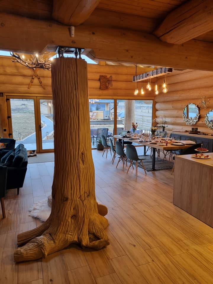 Interior de chalet cu stâlpi sculptați și mobilier din lemn