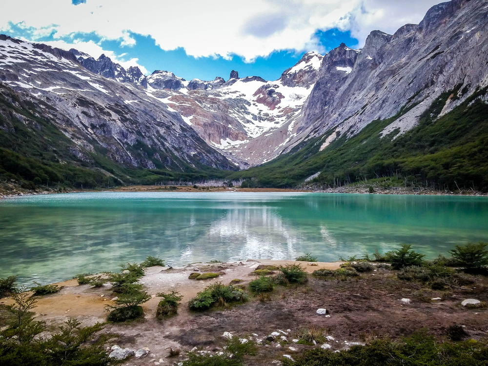 Lac liniștit printre munți cu zăpadă pe vârfuri
