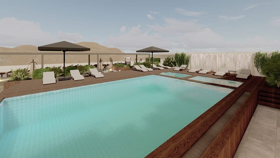 Piscină exterioară cu șezlonguri și umbrele, în fața unui peisaj arid.