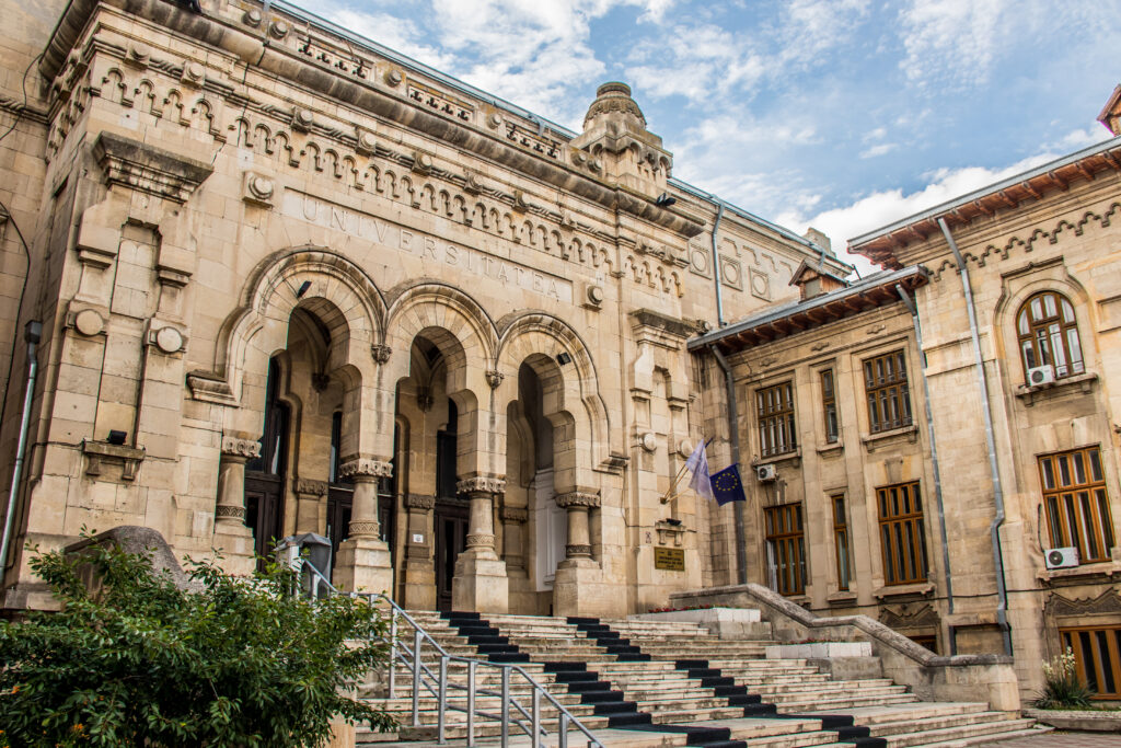 Intrare monumentală din piatră, cu trei arcade și trepte late.