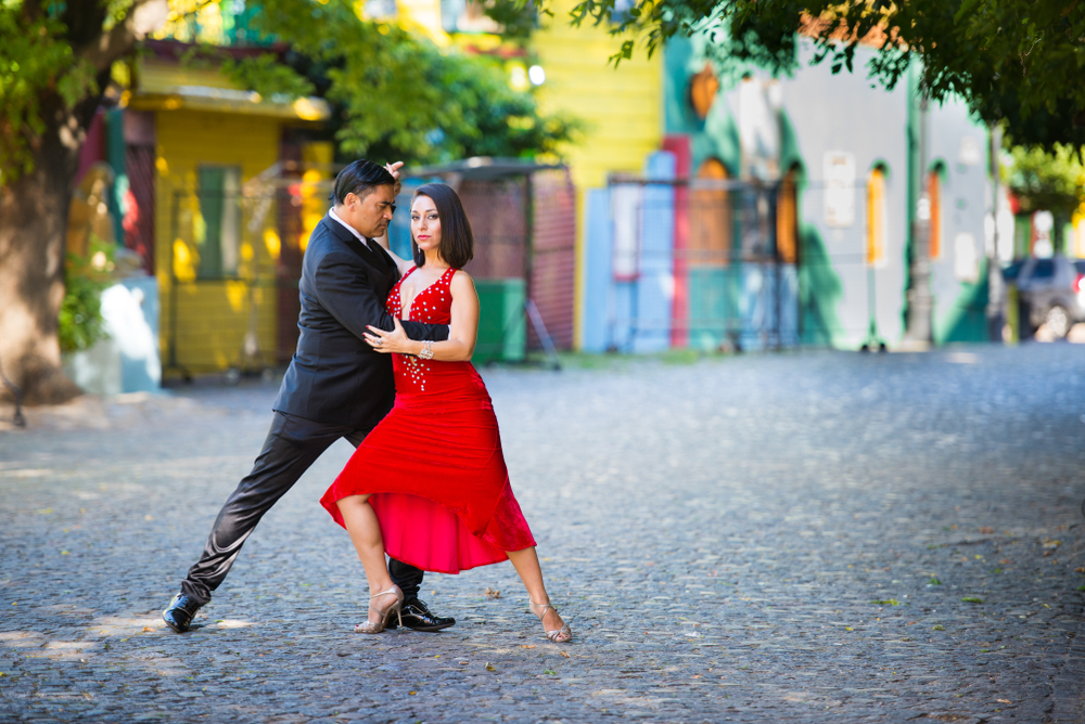 Cuplu dansând tango pe o stradă colorată