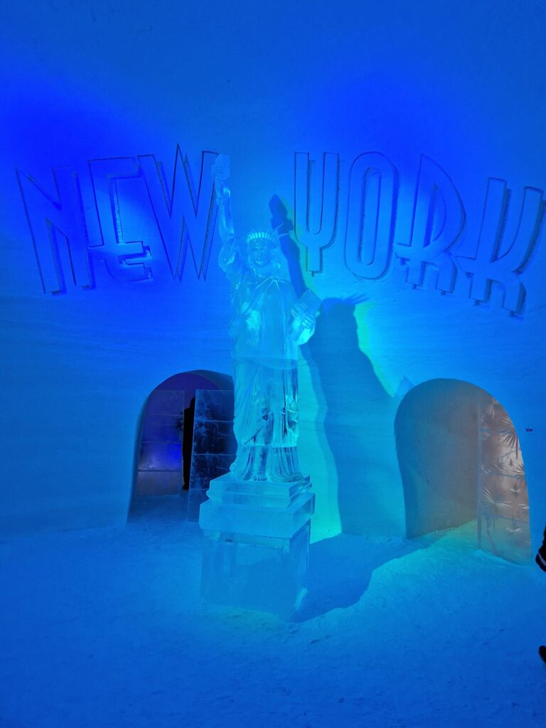 Sculpturi și deschideri arcuite într-o încăpere de gheață iluminată albastru.
