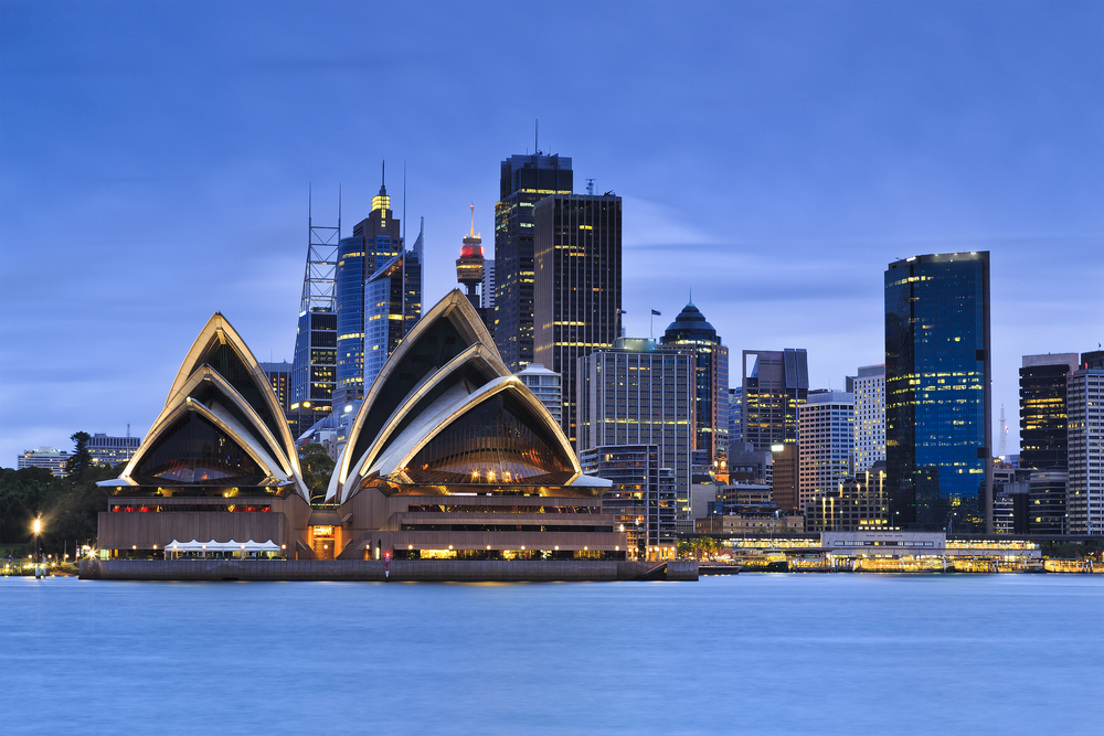 Opera din Sydney iluminată seara, lângă apă