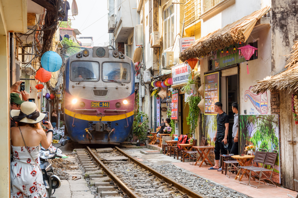 Tren pe o stradă îngustă, între clădiri din Hanoi