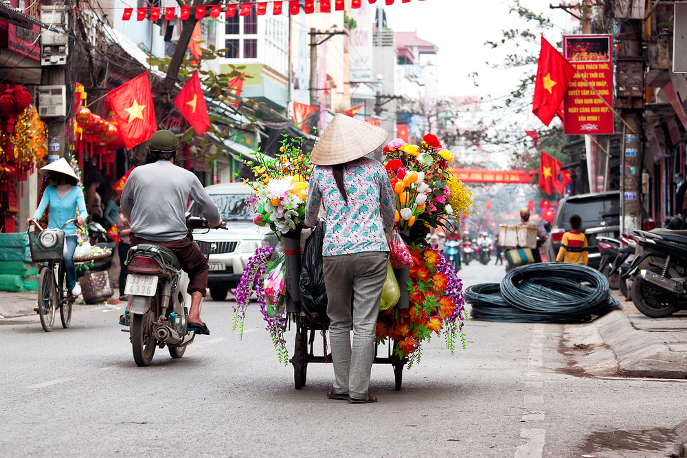 Persoane pe o stradă din Hanoi, lângă magazine
