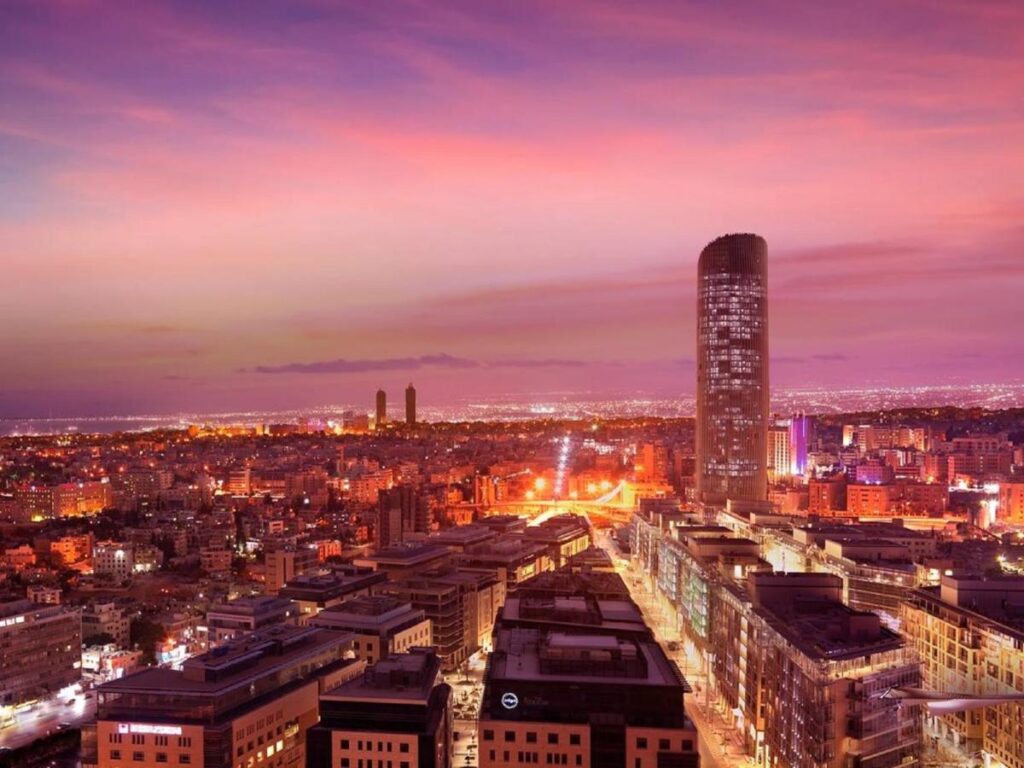 Panoramă urbană la apus, cu un turn înalt și străzi iluminate.
