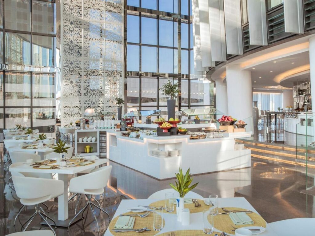 Restaurant luminos cu bufet central și ferestre pe două niveluri.