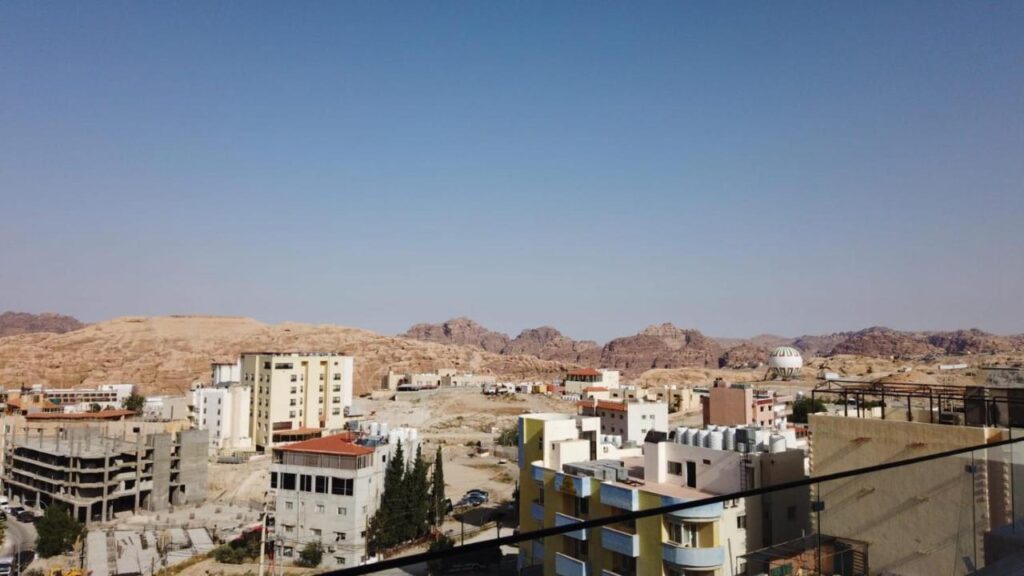 Clădiri joase și blocuri într-un peisaj arid, văzute de la balcon.