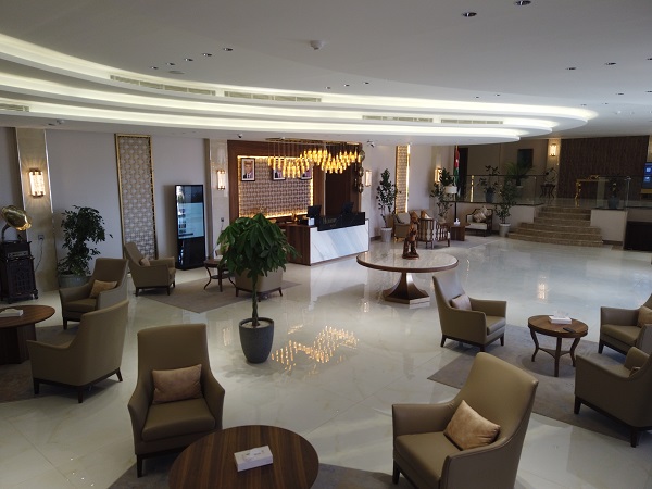 Salon spațios cu fotolii, mese și plante decorative.