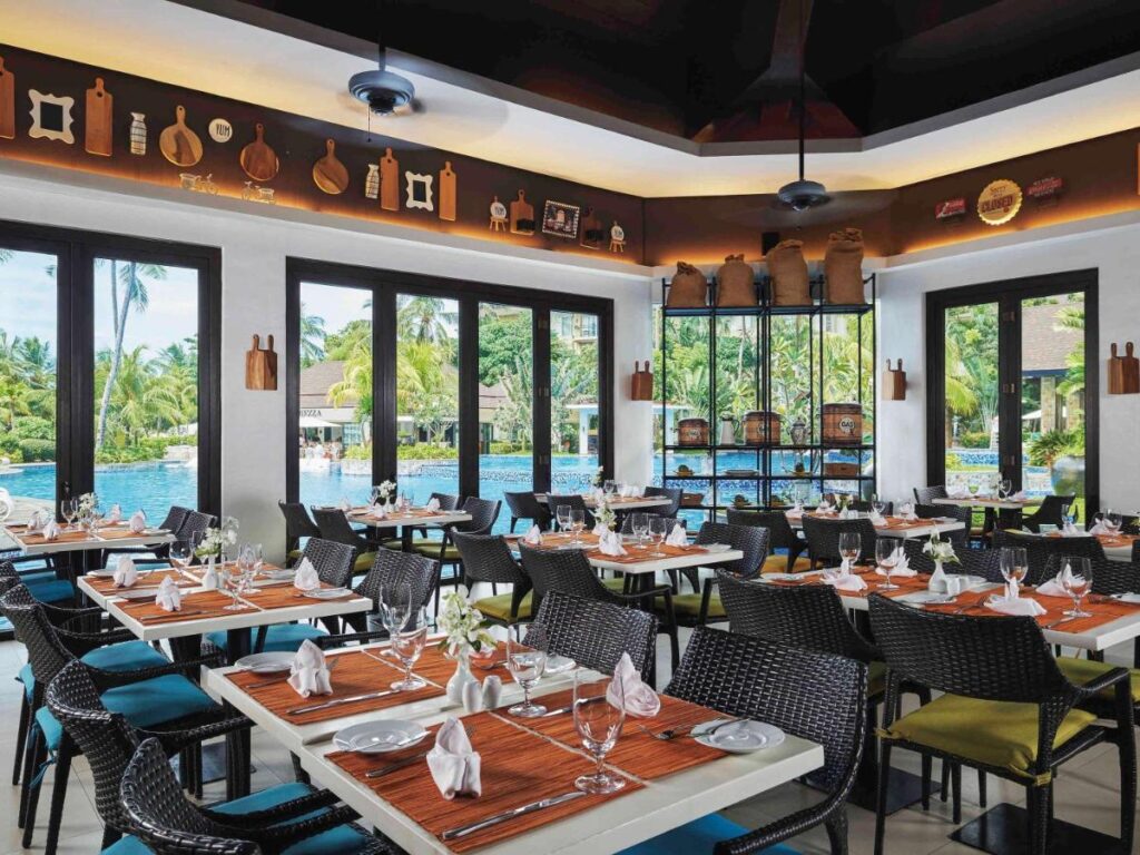 Restaurant cu mese pregătite și ferestre spre vegetație.