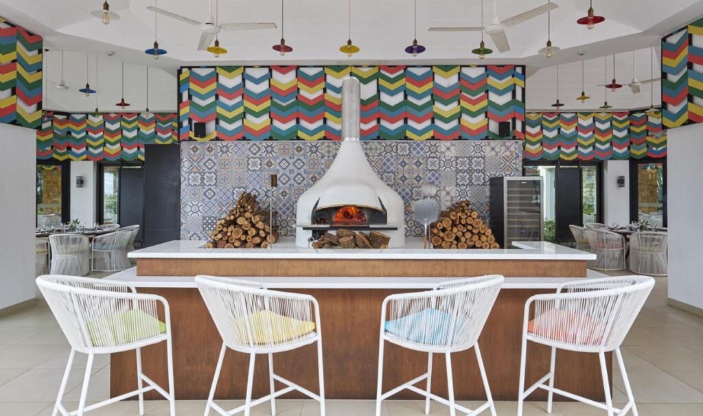 Bar cu scaune albe și cuptor sub decorațiuni multicolore.