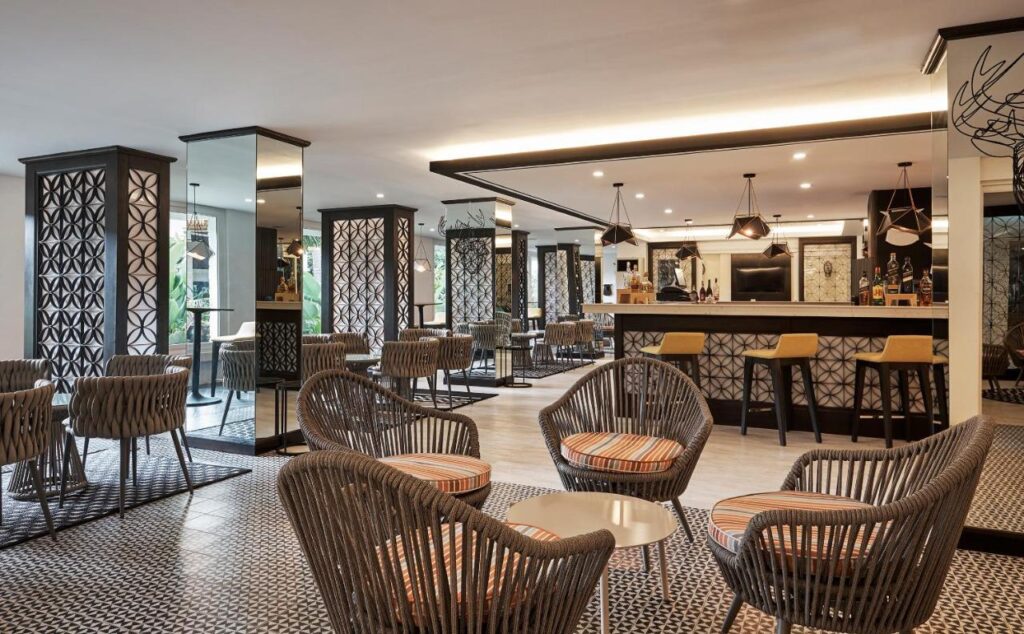 Salon cu fotolii împletite, măsuțe și bar.