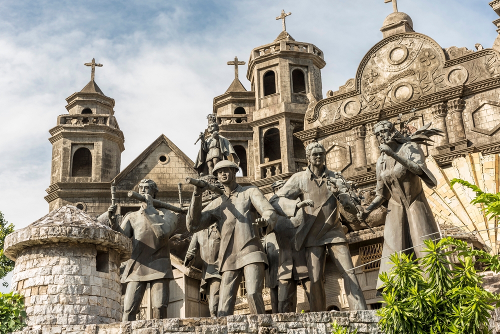 Grup statuar în fața unei fațade de biserică.