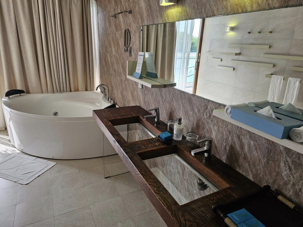 Baie cu cadă ovală și lavoare pe mobilier din lemn.