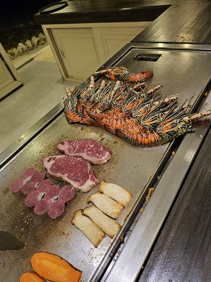 Carne și fructe de mare expuse lângă o plită.