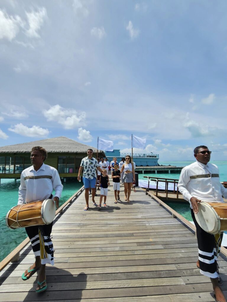 Oameni cu instrumente de percuție pe un ponton din lemn.
