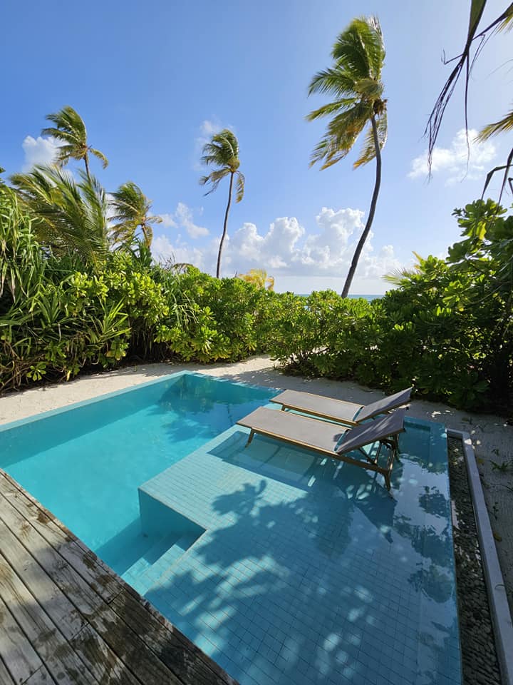 Piscină mică lângă o terasă și vegetație tropicală.