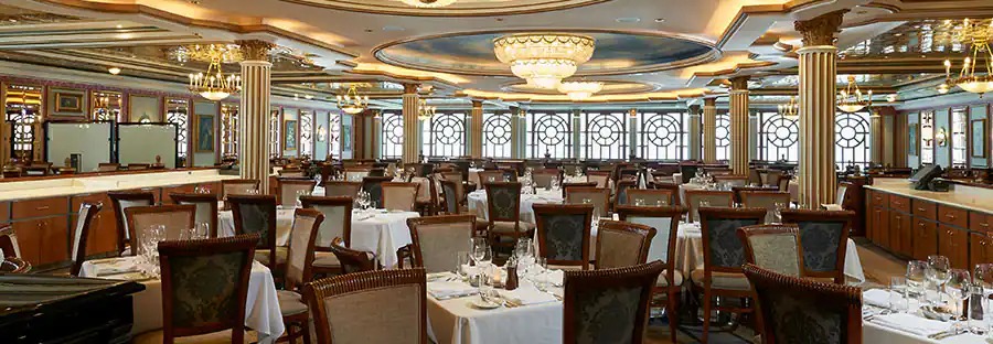 Sală de restaurant cu mese pregătite și plafon ornamentat.