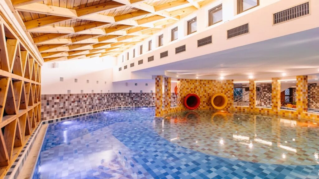 Piscină interioară cu apă albastră și pereți cu mozaic