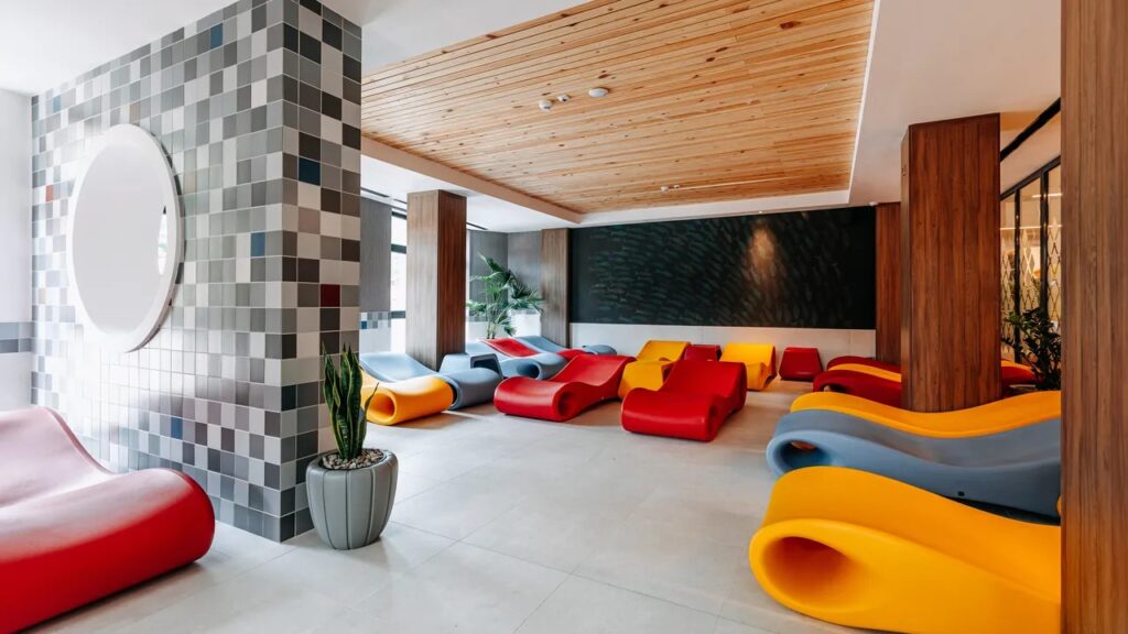 Spațiu de relaxare cu șezlonguri colorate și ferestre mari