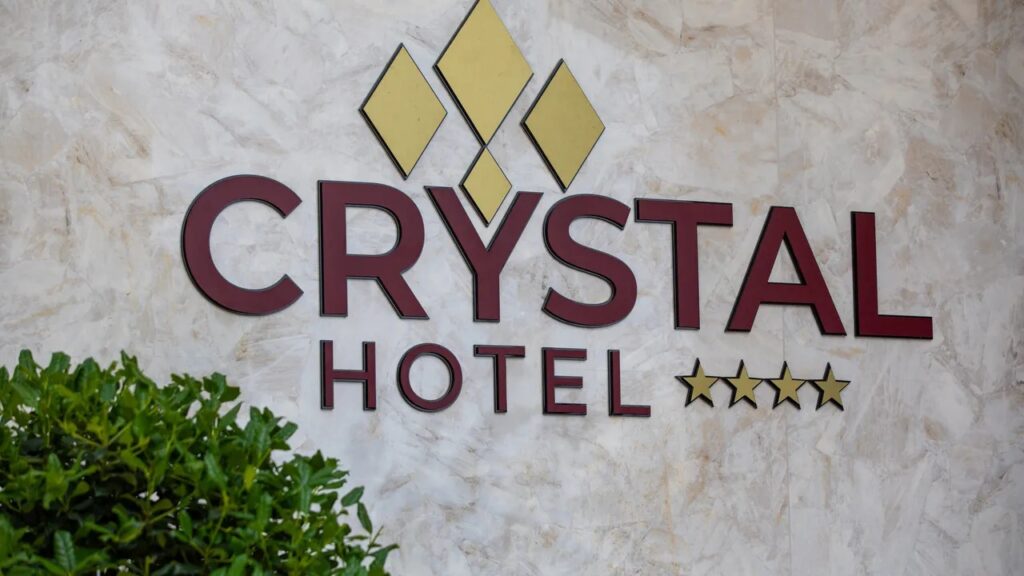 Sigla Crystal Hotel pe un perete deschis la culoare