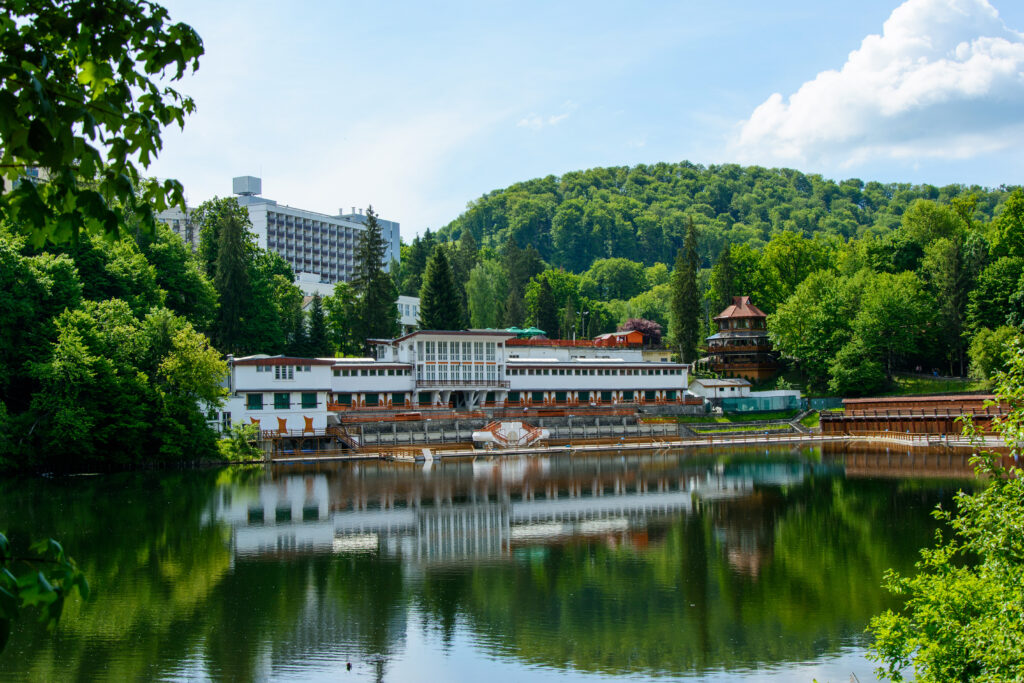 Clădire pe malul unui lac, lângă dealuri împădurite