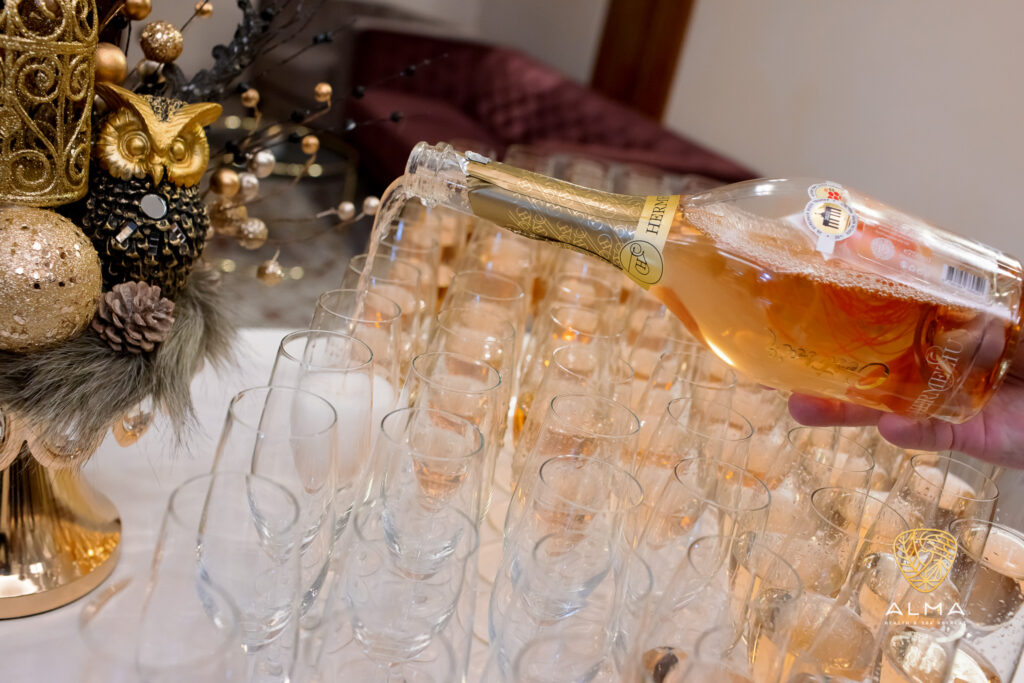 Băutură turnată dintr-o sticlă într-un șir de pahare festive.