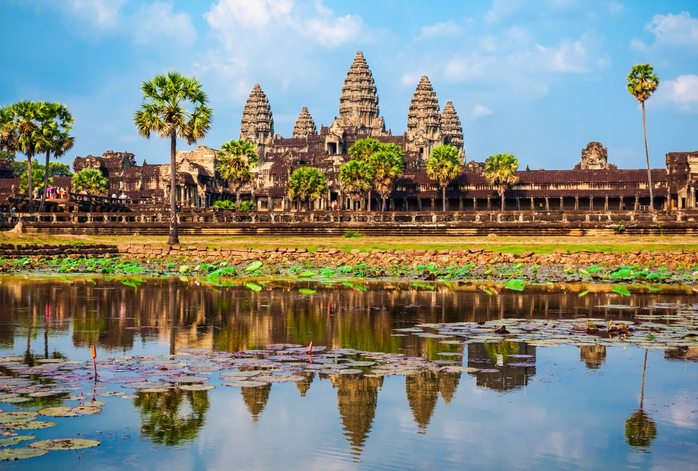 Turnurile Angkor Wat reflectate în apă, printre palmieri