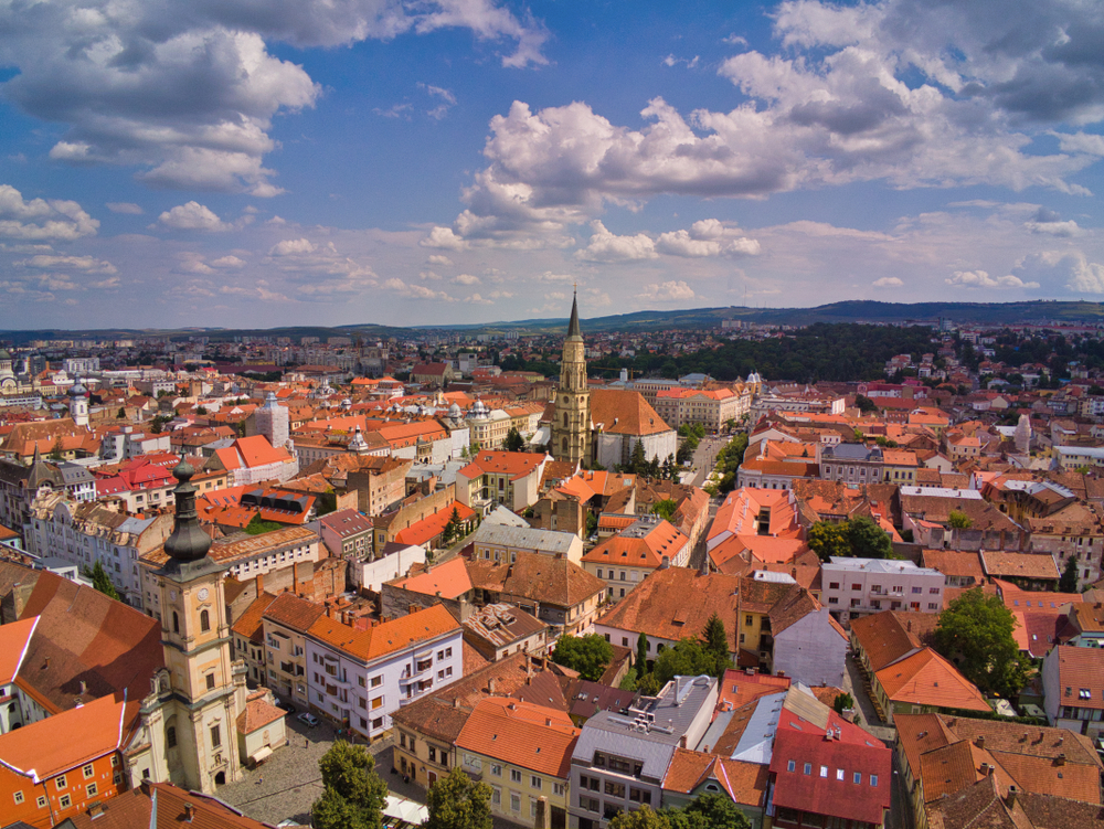 Acoperișuri roșii și turnuri într-o panoramă a Clujului