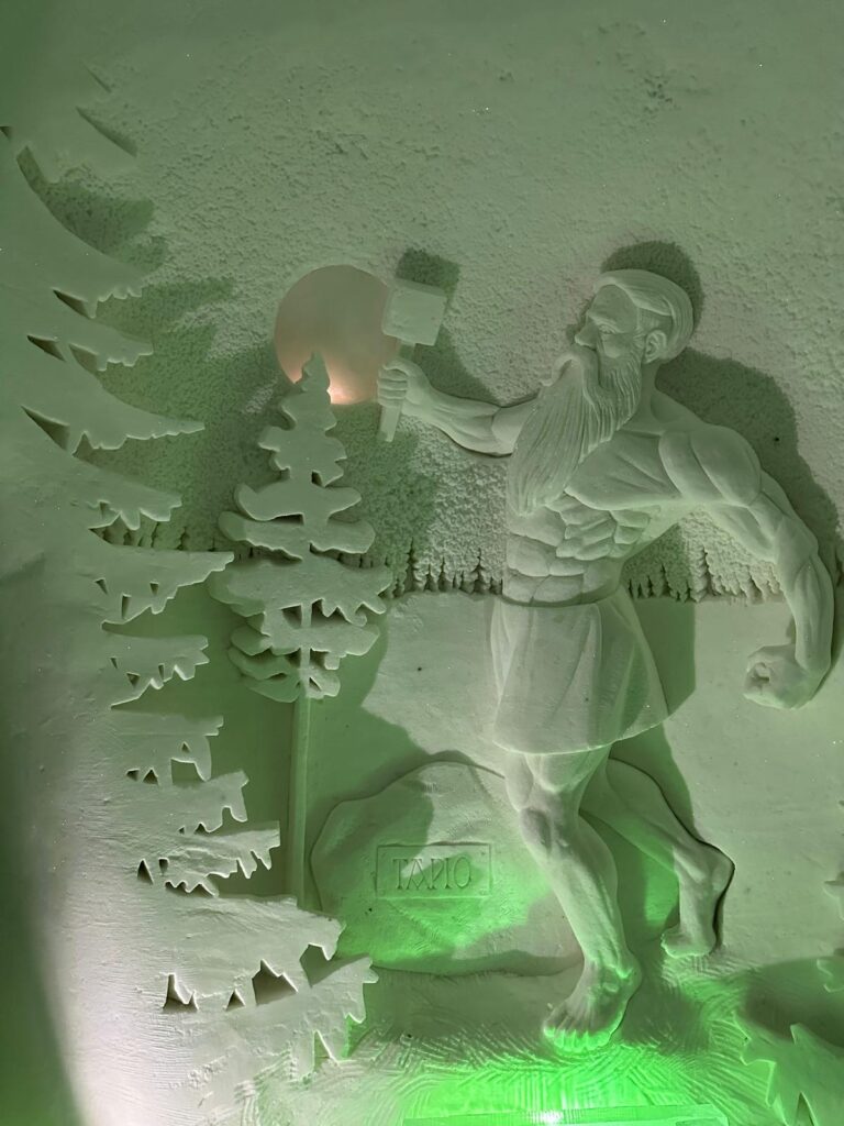 Personaj sculptat în gheață, lângă forme de arbori