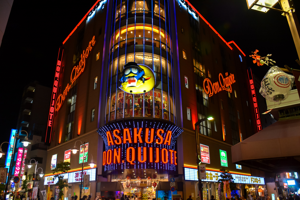 Fațadă comercială cu reclame luminoase, fotografiată noaptea