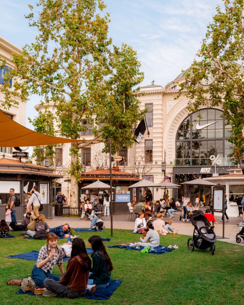 Fântână și clădiri comerciale, într-o piață cu arbori