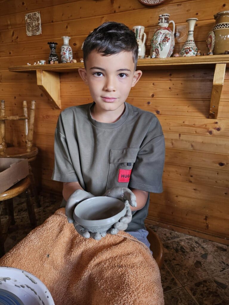 Copil modelând lutul într-un atelier cu mobilier din lemn