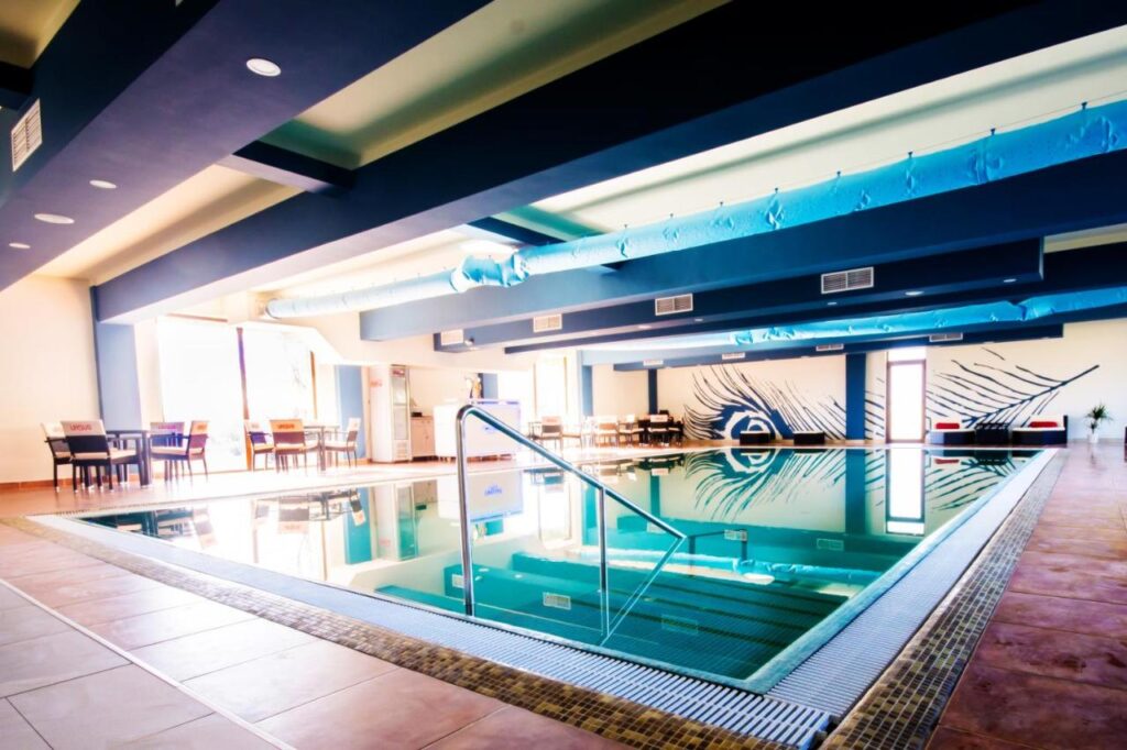 Piscină interioară cu șezlonguri, ferestre și iluminare colorată