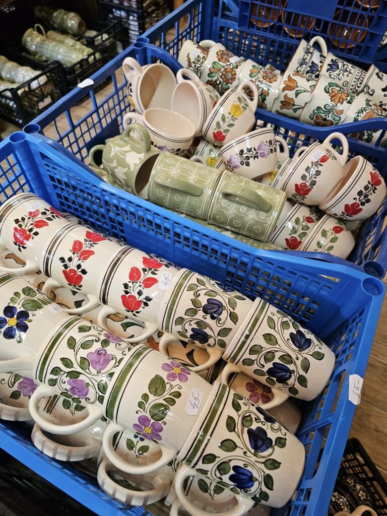 Obiecte ceramice pictate, aranjate în coșuri și rafturi