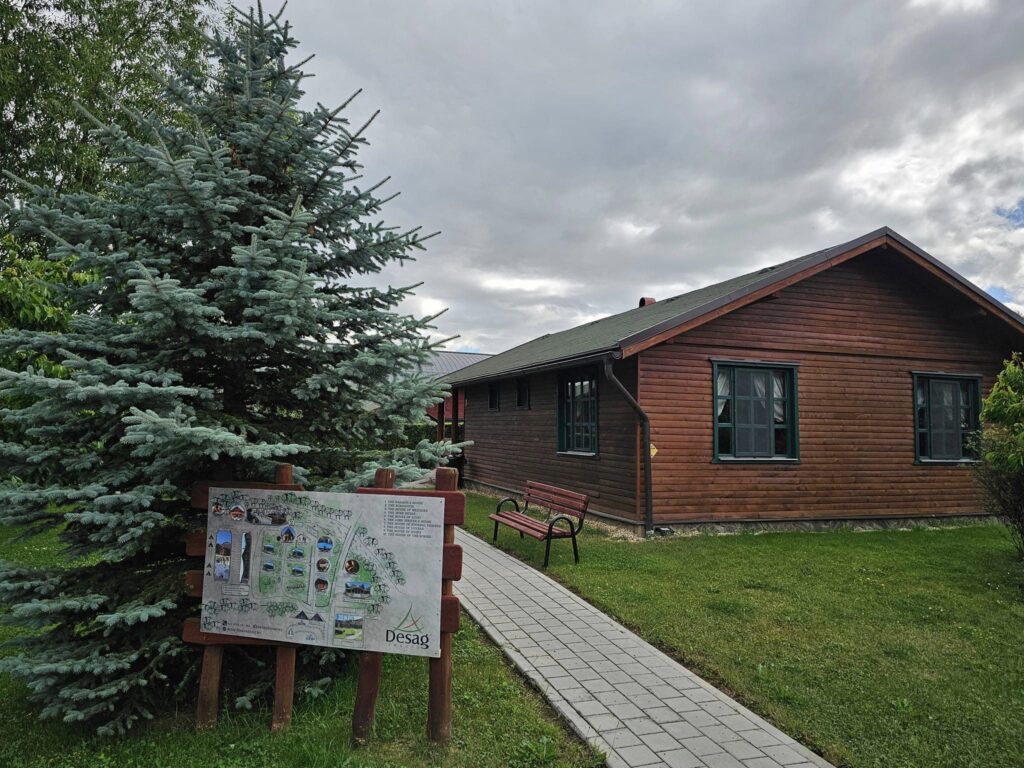 Cabană de lemn lângă un panou și arbori