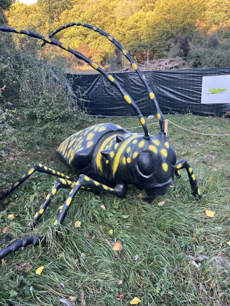 Sculptură de insectă galbenă și neagră între arbori