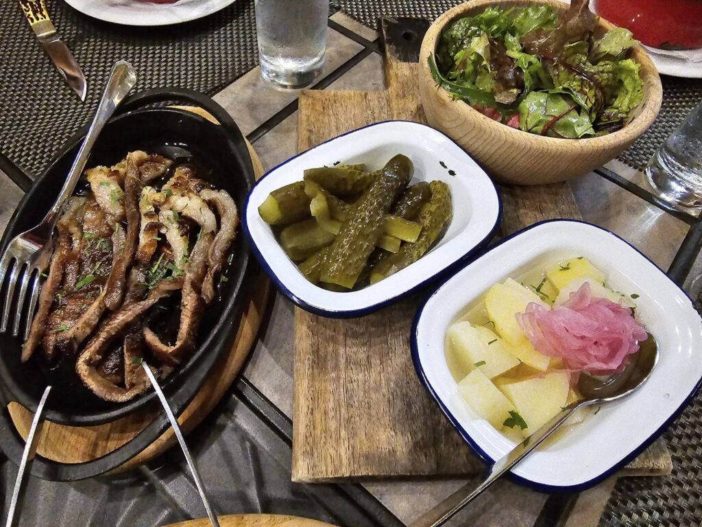 Farfurii cu carne, legume și garnituri pe o masă