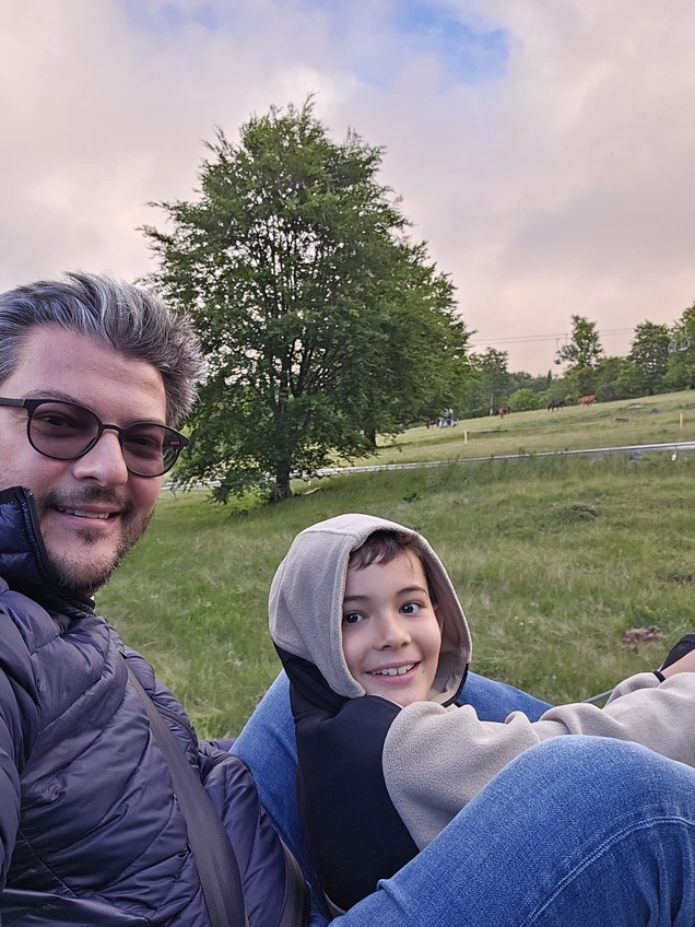 Adult și copil lângă un lac cu vegetație