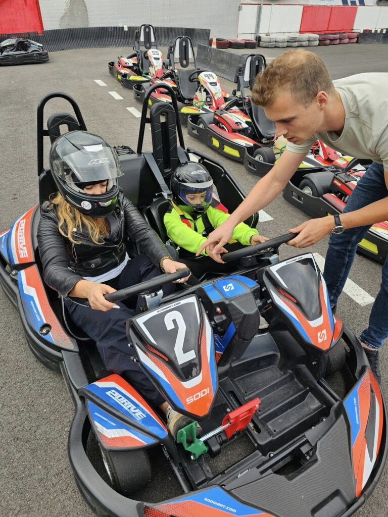 Copil așezat într-un kart, pe un circuit exterior