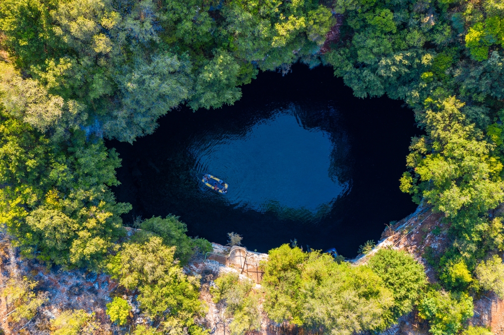 Lac întunecat într-o deschidere circulară înconjurată de vegetație densă