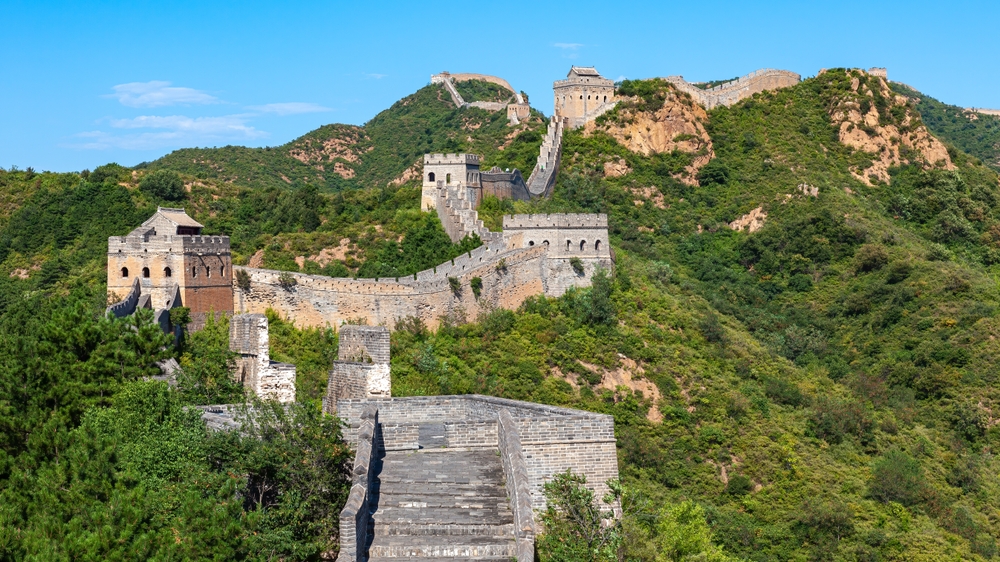Marele Zid Chinezesc printre dealuri acoperite de vegetație